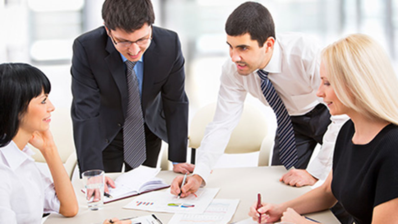 two men and two women professionally dressed working together at a conference table