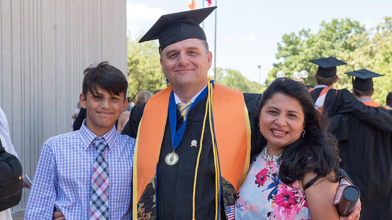 A husband/father celebrating his graduation with his wife and son.