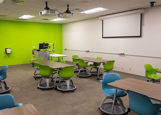 LDB 208 - a large room with many tables and one green wall.