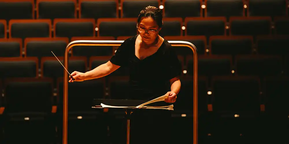 An SHSU graduate student conducts in the on-campus concert hall.