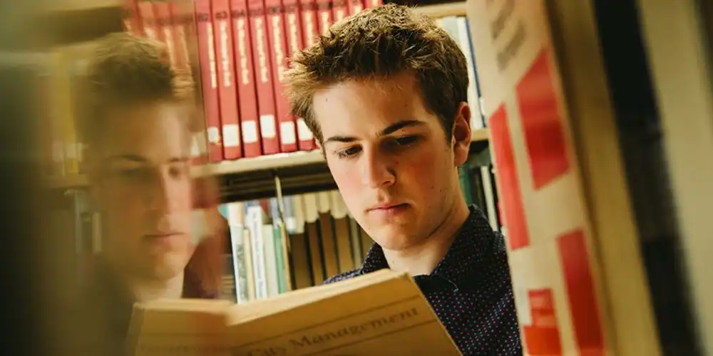 An SHSU graduate student reads a book about city management in the library.