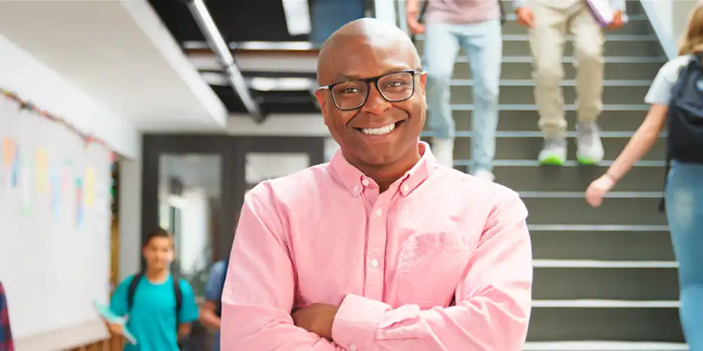 An SHSU graduate student stands in the hallway of the school where he works full-time while taking classes.
