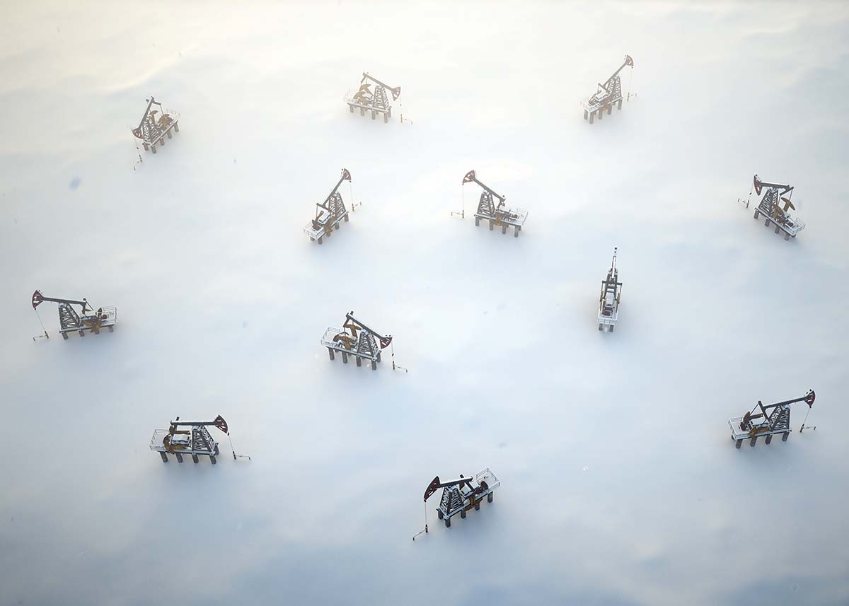 A collection of oil rigs in the ocean being shrouded by fog.