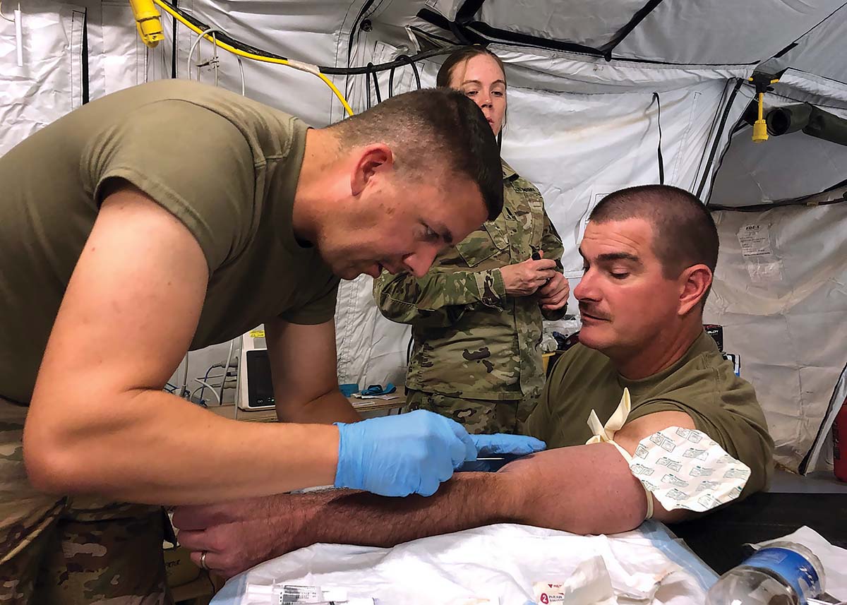 John Manning taking blood from a fellow member of the armed forces.
