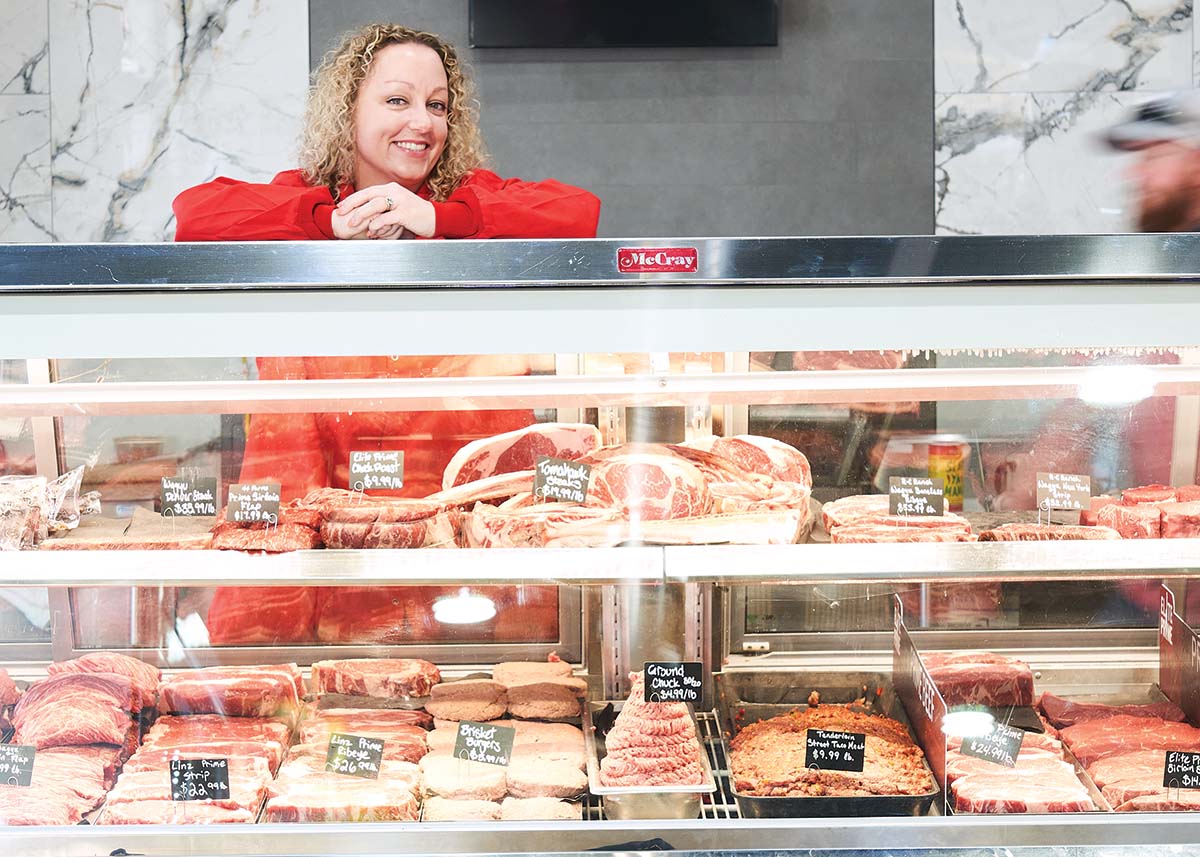 Ami Stone leaning on a meat display case.