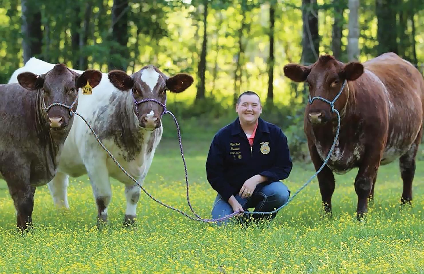 Tyler D. Root poses with three cows.