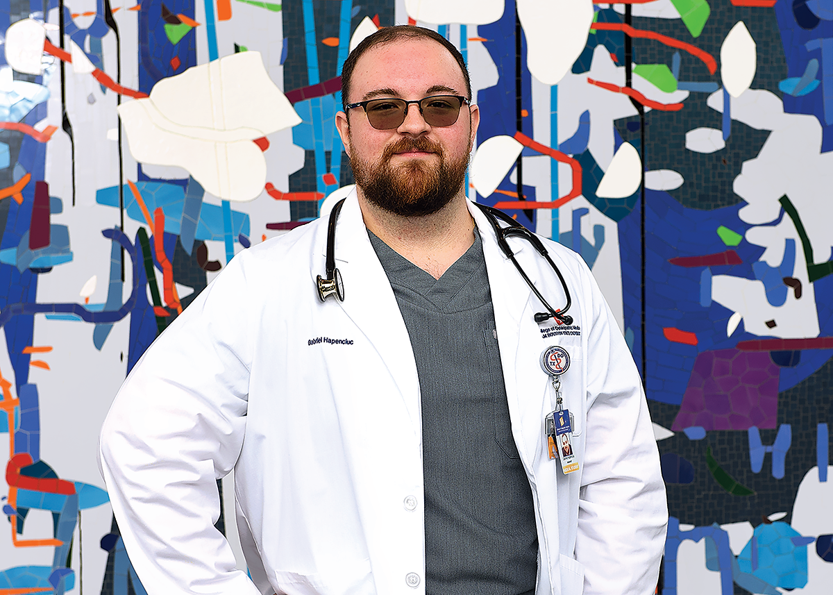 Gabriel Hapenciuc wearing a white medical robe while posing against a mosaic.