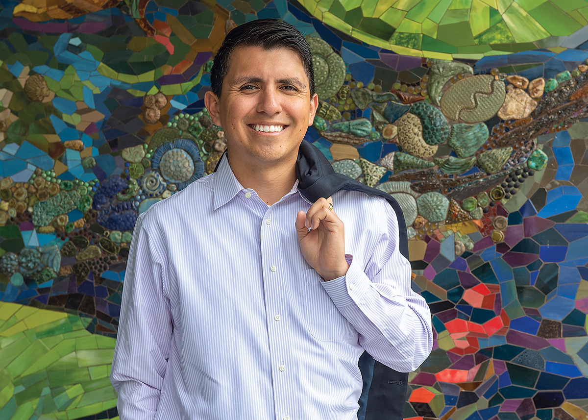 Noe Negrete poses against a beautiful blue and green mosaic.