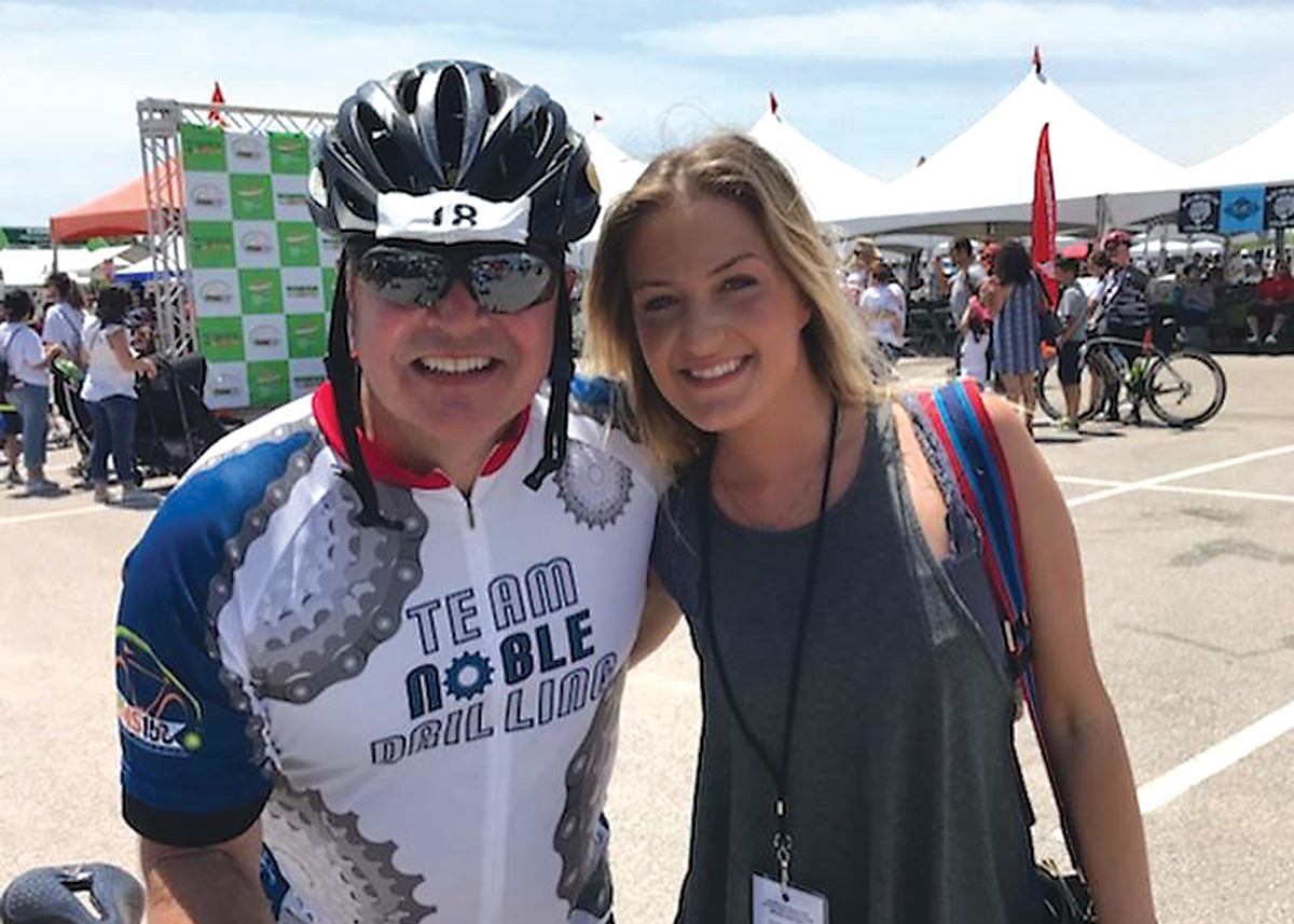 Robert Pohl wears cycling gear and poses for a photo in a parking lot.