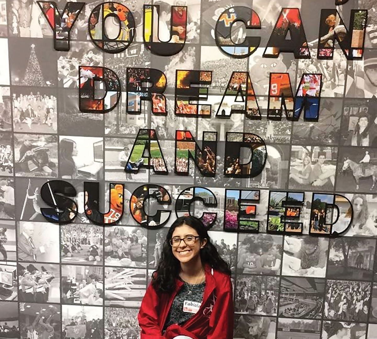 Fabiola Cardona posing under a sign that says You Can Dream and Succeed