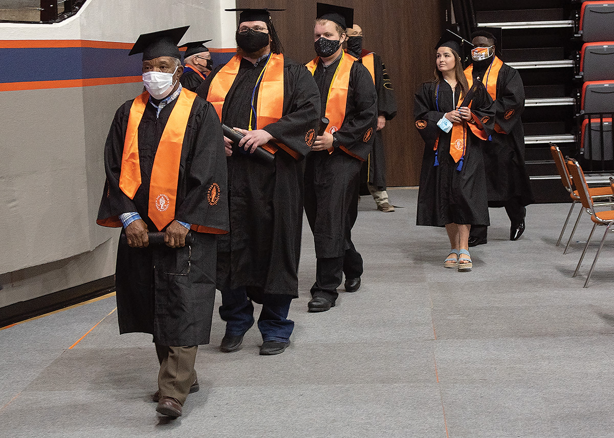 James Floyd walking on the floor of the coliseum during graduation in a line with his fellow graduates.