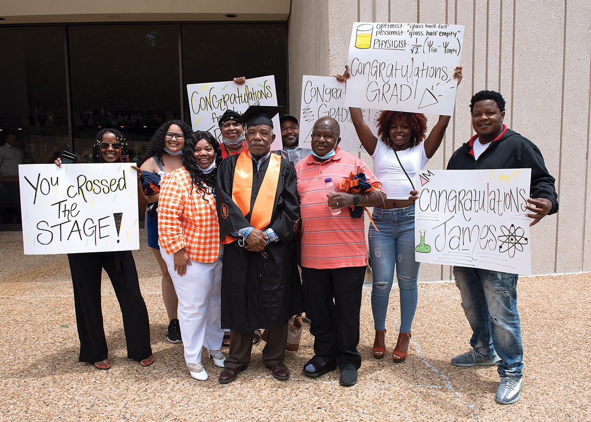 James Floyd standing with his family after the gradution ceremony. They are holding signs that celebrate his accomplishment.