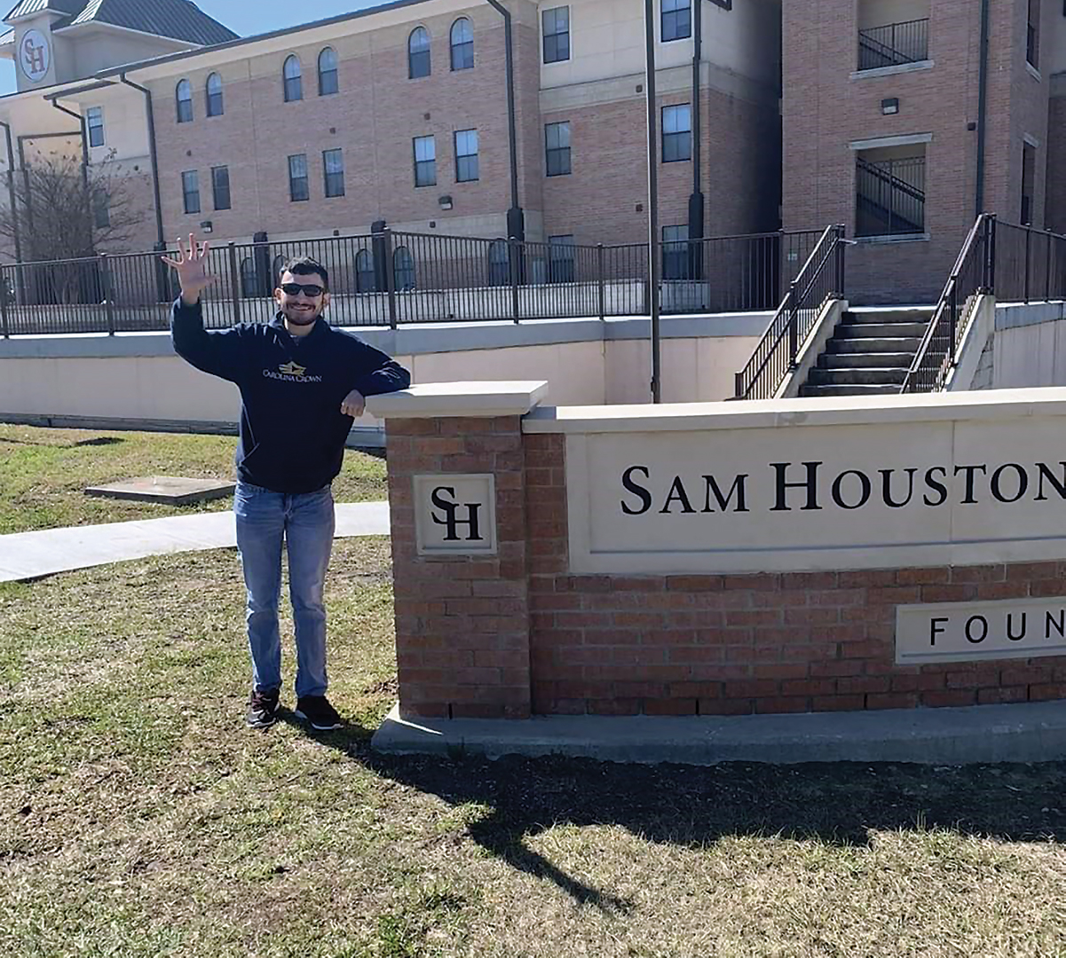 Mark Woods Posing with the Sam Houston sign at the corner of campus.