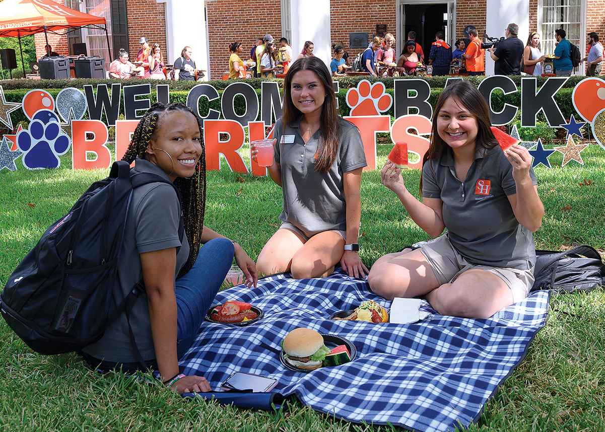 Two Bearkats sitting on a picnic blanket during the Bearkat Welcome Week Picnic.