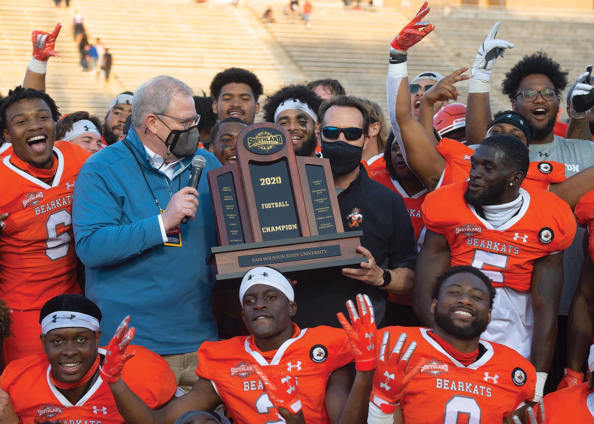 Bearkat Football players and Coach K.C. Keeler hold a trophy and celebrate their victory.