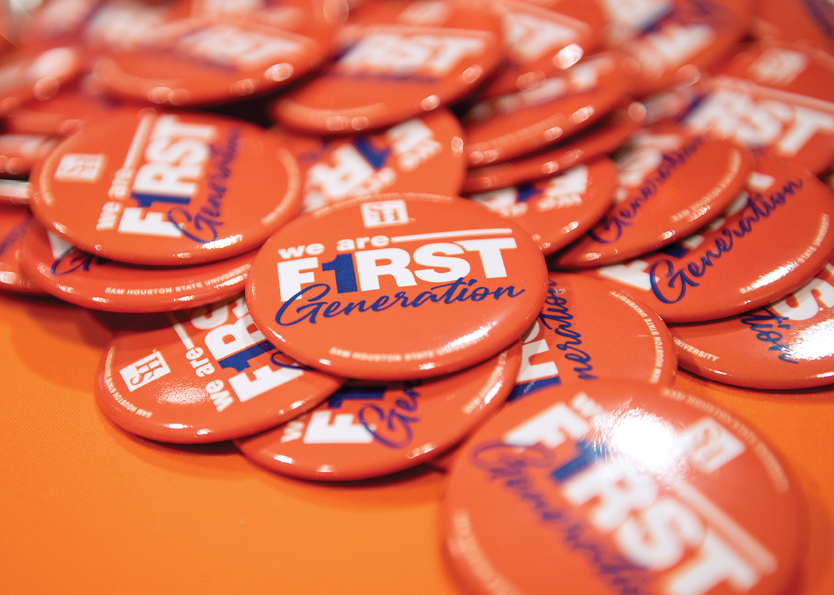 A pile of orange buttons that say We Are First Generation
