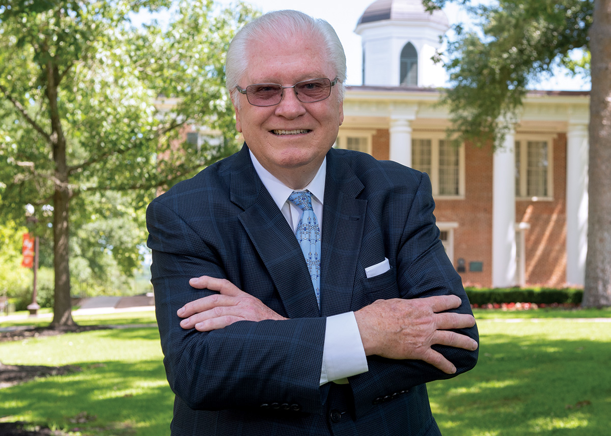 Bob Roush poses confidently in front of Austin Hall on the SHSU campus.