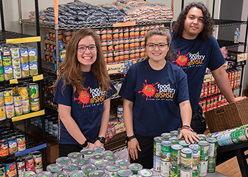 Food Pantry volunteers pose in the shelves full of food.