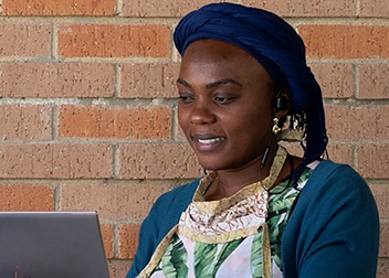 A student smiling at their laptop.