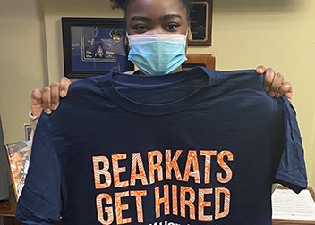 A student holding up a t-shirt with the Phrase 'Bearkats Get Hired'.