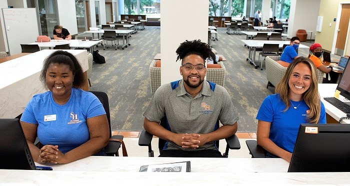 three mentors sit at front desk of center