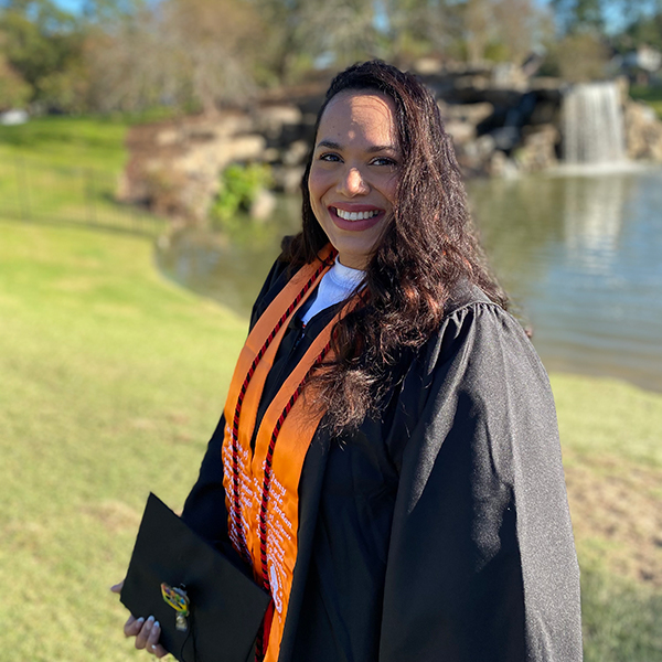 Tiffany Taylor-Jordan with cap and gown at a lake.