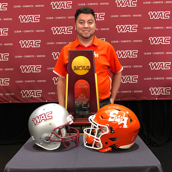 Carlos Zimmerman posing with the National Championship trophy and Western Athletic Conference Background.