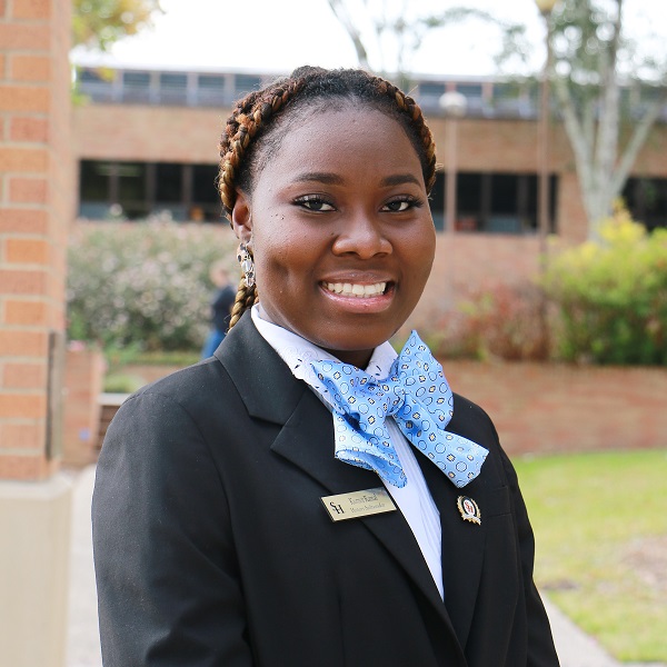 Kismot Kamal wearing professional attire posing at the SHSU Bell Tower.