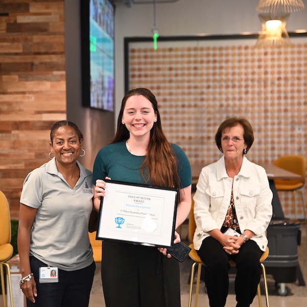 Melissa Baumgartner, center, holds an award certificate commemorating her first-place win in a business presentation contest during her internship at HP.