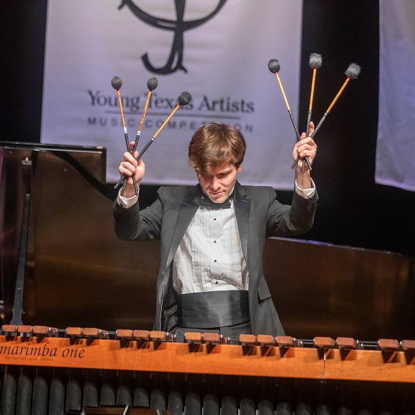 Mateo Seghezzo confidently holds 6 drumsticks trained on the marimba below.